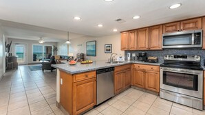 A modern kitchen with wooden cabinets, stainless steel appliances, and a granite countertop. - Suntide II 301 - Oceanfront Condo, BBQ's, Sand Volleyball, Sun Deck, Beachfront Pool & Spa (South Padre Island)