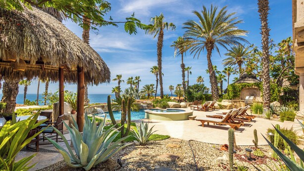 Un resort con piscina, sillas de descanso y palmeras.