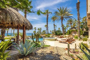 A resort with a pool, lounge chairs, and palm trees.