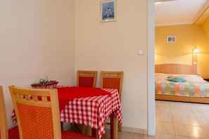 A dining area with a red and white checkered tablecloth, wooden chairs, and a small table with a basket. - Aqua Blue Hotel (Hajduszoboszlo)