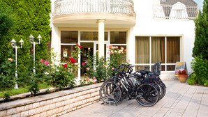 Entrada de hotel con fachada blanca, un balcón curvo con barandillas metálicas y una fila de bicicletas estacionadas afuera.
