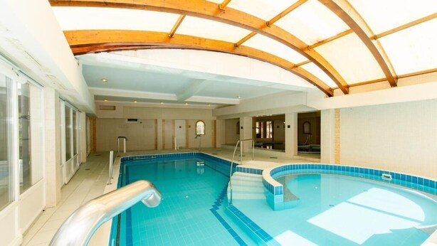 Una piscina interior con techo de madera y paredes de azulejos.
