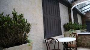 A patio area with a white table and two chairs, a large potted plant, and a brick wall. - Number 8 The Townhouse (Londonderry)