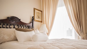 A neatly made bed with a wooden headboard, a framed picture on the wall, and beige curtains. - Number 8 The Townhouse (Londonderry)
