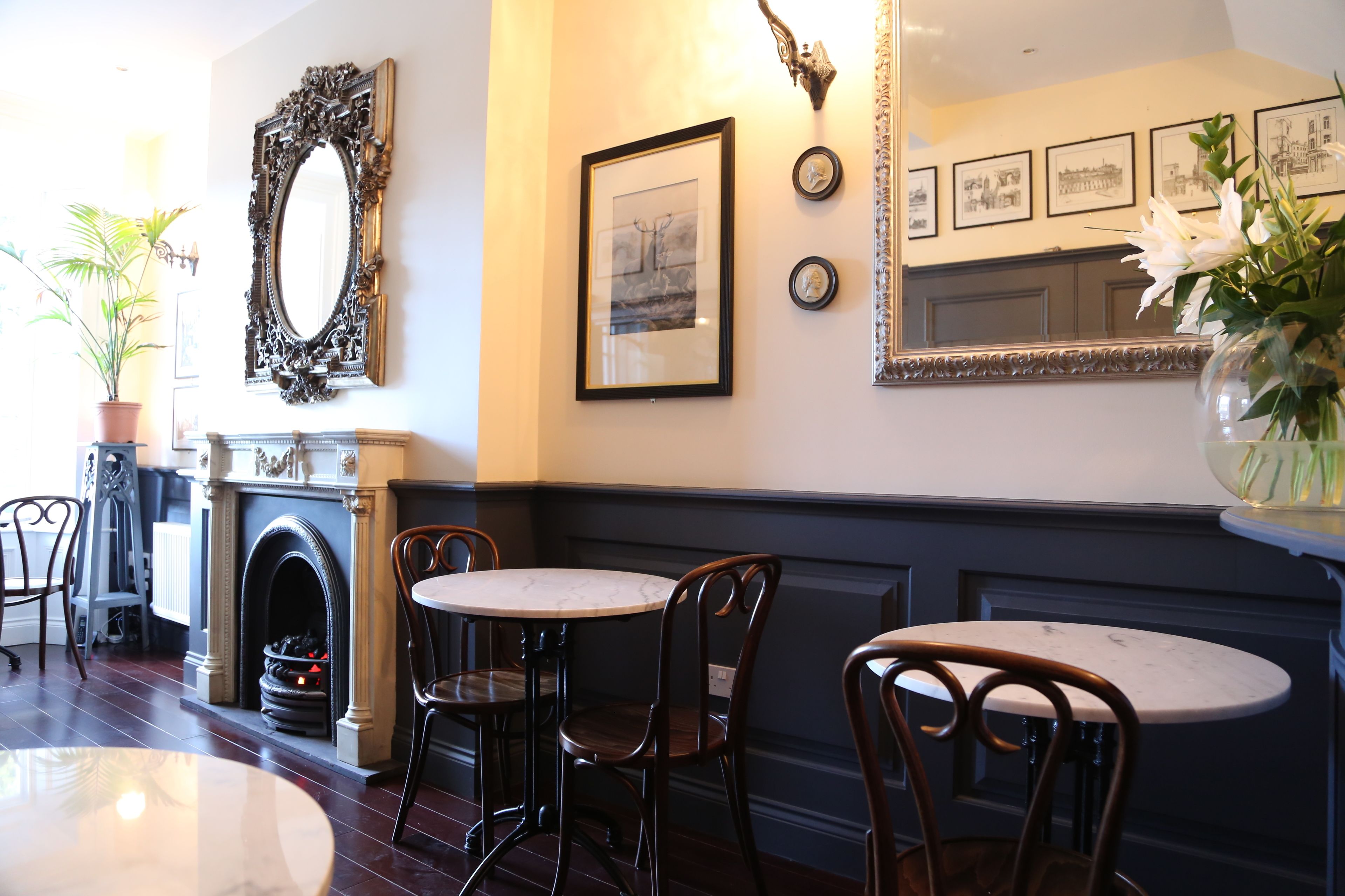 A dining area with a fireplace, framed artwork, and a mirror.