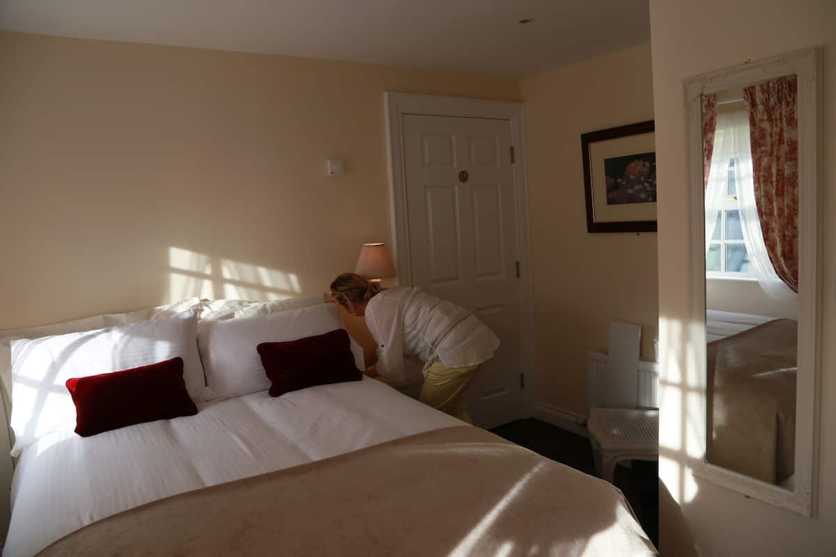 Ein Hotelzimmer mit einem Bett, einer Tür, einem Fenster mit Vorhängen und einem Heizkörper.