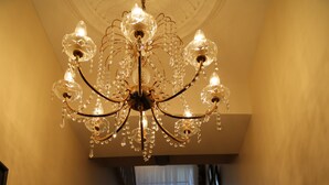 A grand staircase with a crystal chandelier, wooden handrails, and a view of a room with a window and curtains. - Number 8 The Townhouse (Londonderry)