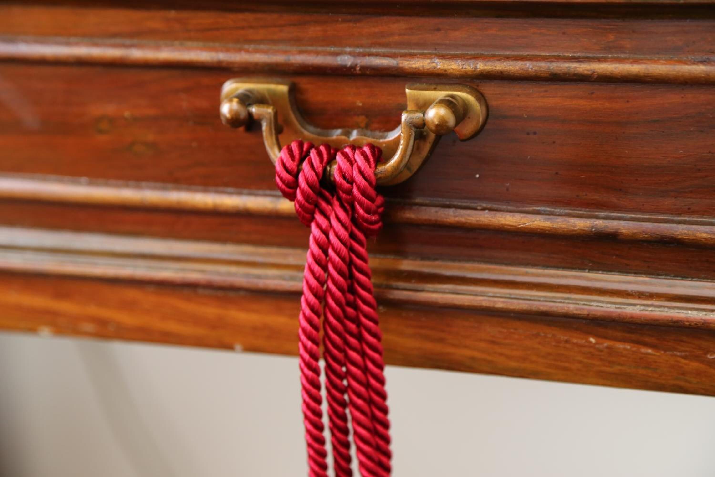 A wooden door with a brass handle and a red rope tied to it.