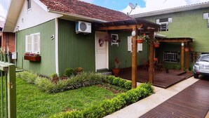 A green building with a tiled roof, a covered porch, and a car parked in front. - Residencial Vista do Centro Gramado (Gramado)
