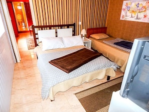 Una habitación de hotel con una cama, dos mesitas de noche, un televisor y un cuadro en la pared.