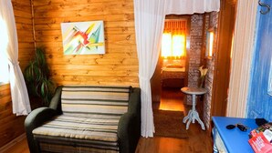 A cozy cabin interior with a striped sofa, a painting on the wall, and a small table with a vase. - Residencial Vista do Centro Gramado (Gramado)