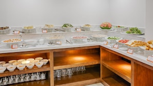A buffet setup with various food items and utensils. - Merry Hotel (Da Nang)