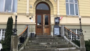 A building with the sign "Stadshotell" above the entrance, featuring a wooden door, stone steps, and a flag.