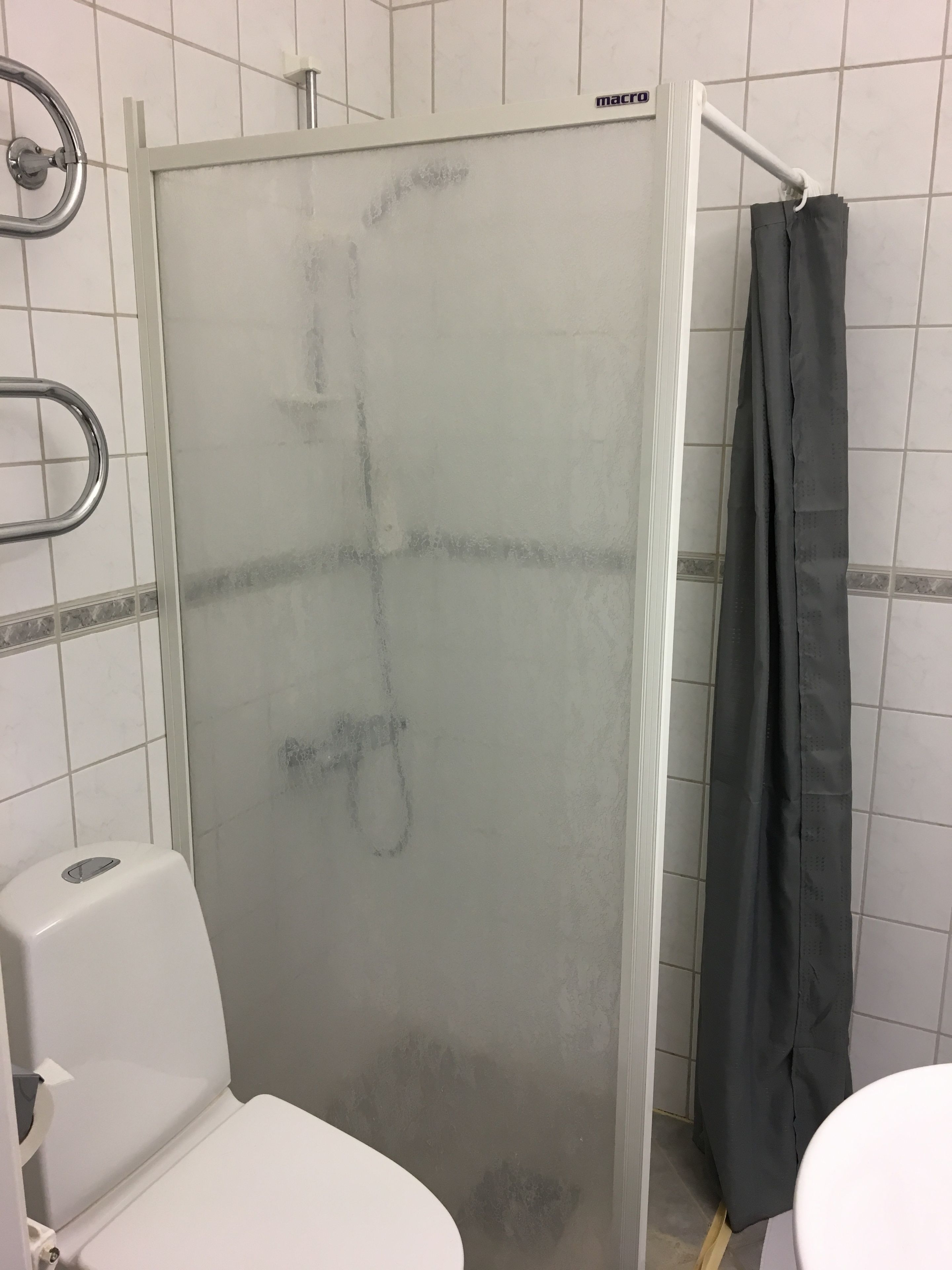Un baño con cabina de ducha de vidrio, inodoro blanco y barra para toallas.