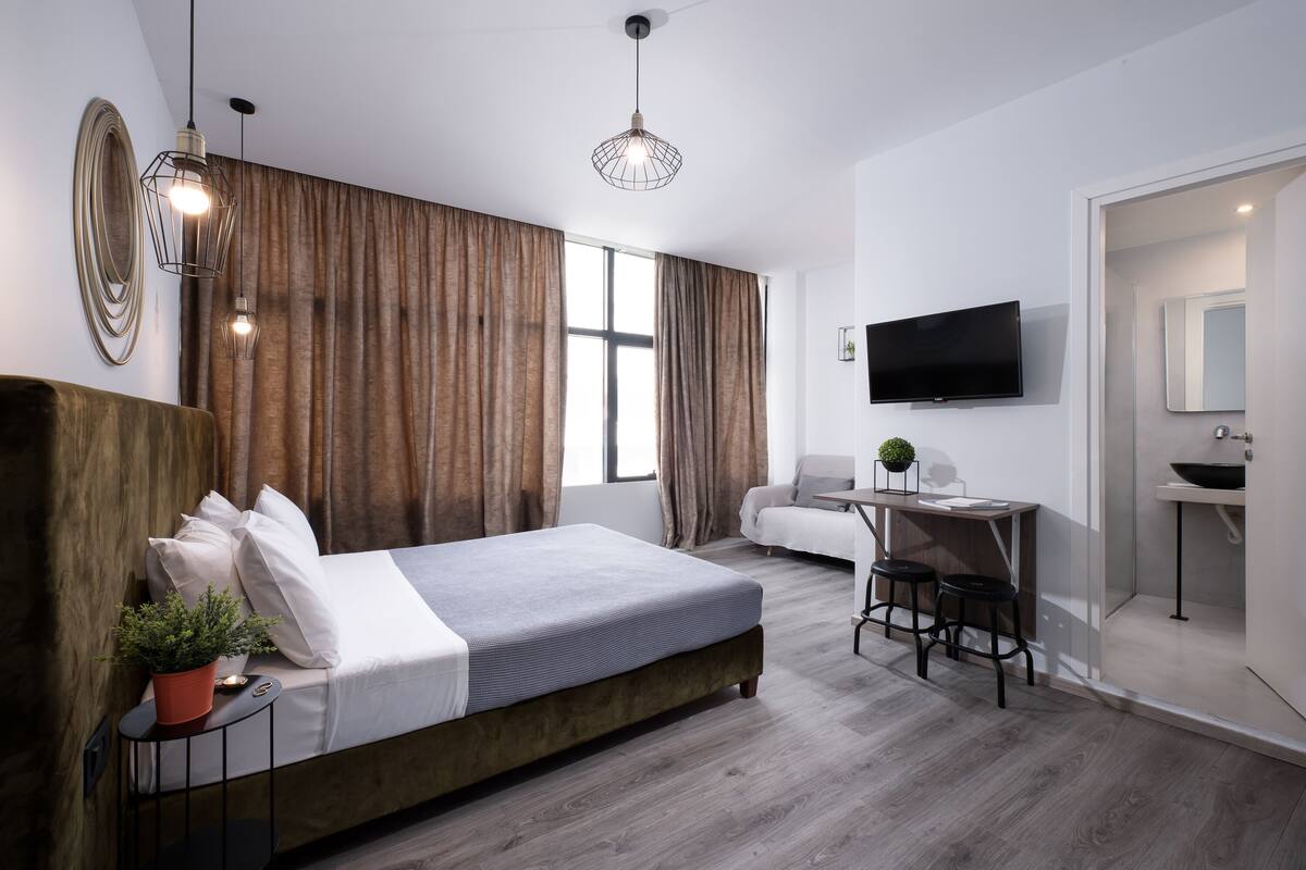 Ein modernes Hotelzimmer mit einem großen Bett, einem Schreibtisch, einem Fernseher und einem Badezimmer.