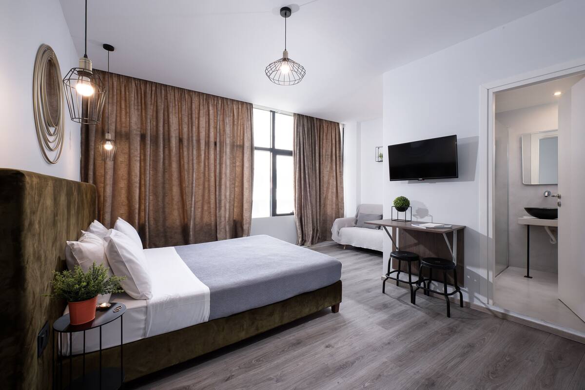 Ein modernes Hotelzimmer mit einem großen Bett, einem Schreibtisch, einem Fernseher und einem Badezimmer.