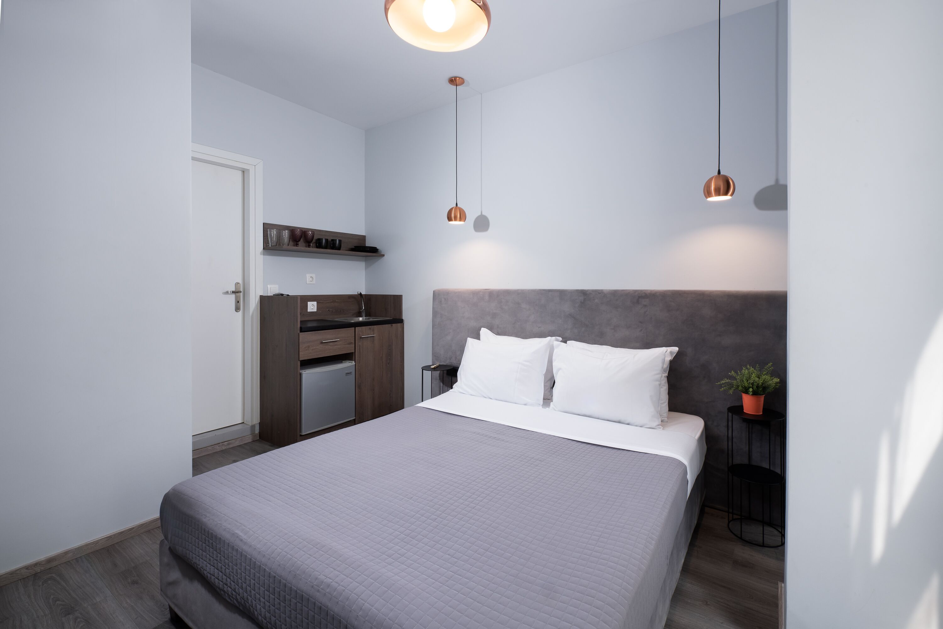 A modern bedroom with a bed, bedside table, and a small potted plant.