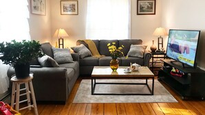 Un salon comprenant un canapé, une table basse, un téléviseur et des objets de décoration.