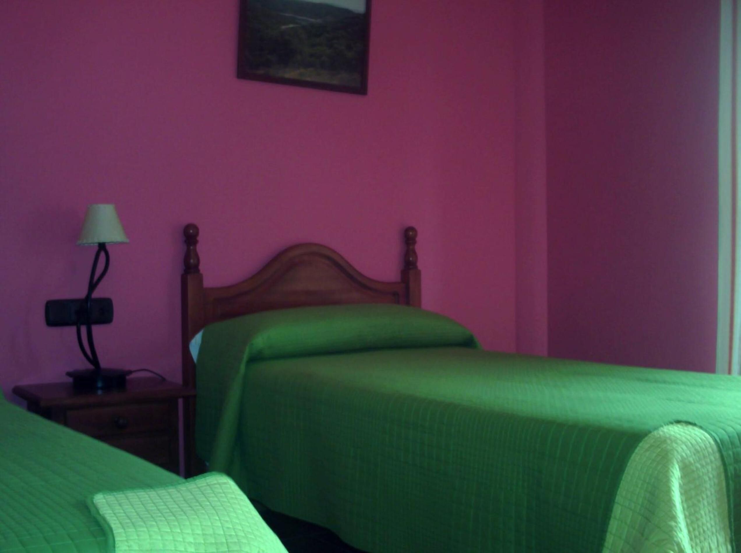 Une chambre avec deux lits, une table de chevet avec une lampe et un tableau au mur.