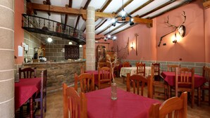 A restaurant with wooden beams, stone walls, and red tablecloths. - Casa Rural La Breña (Talavan)