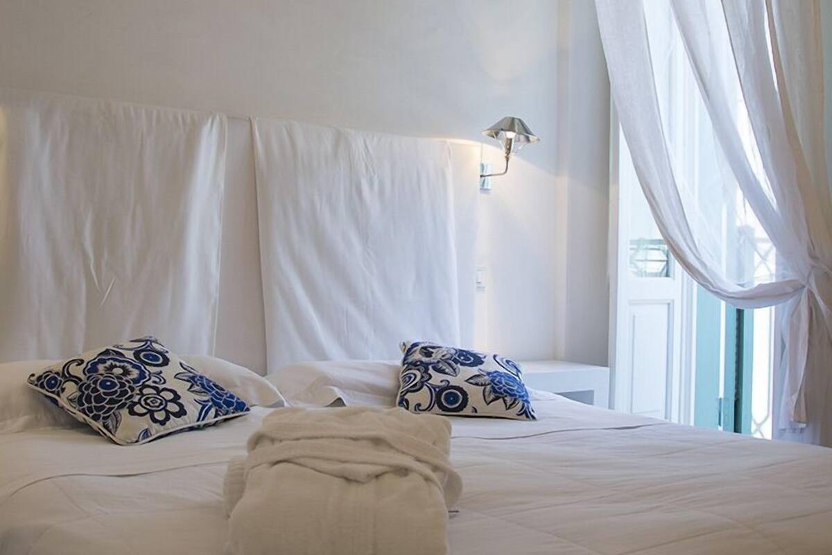 A neatly made bed with white linens, two patterned pillows, and a folded towel.