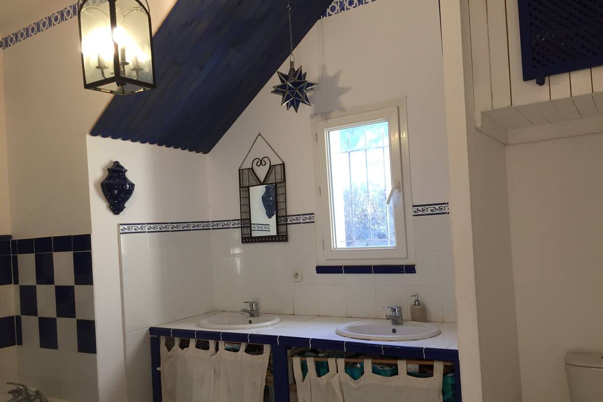A bathroom with two sinks, a window, a mirror, and decorative elements like a star and a lantern.