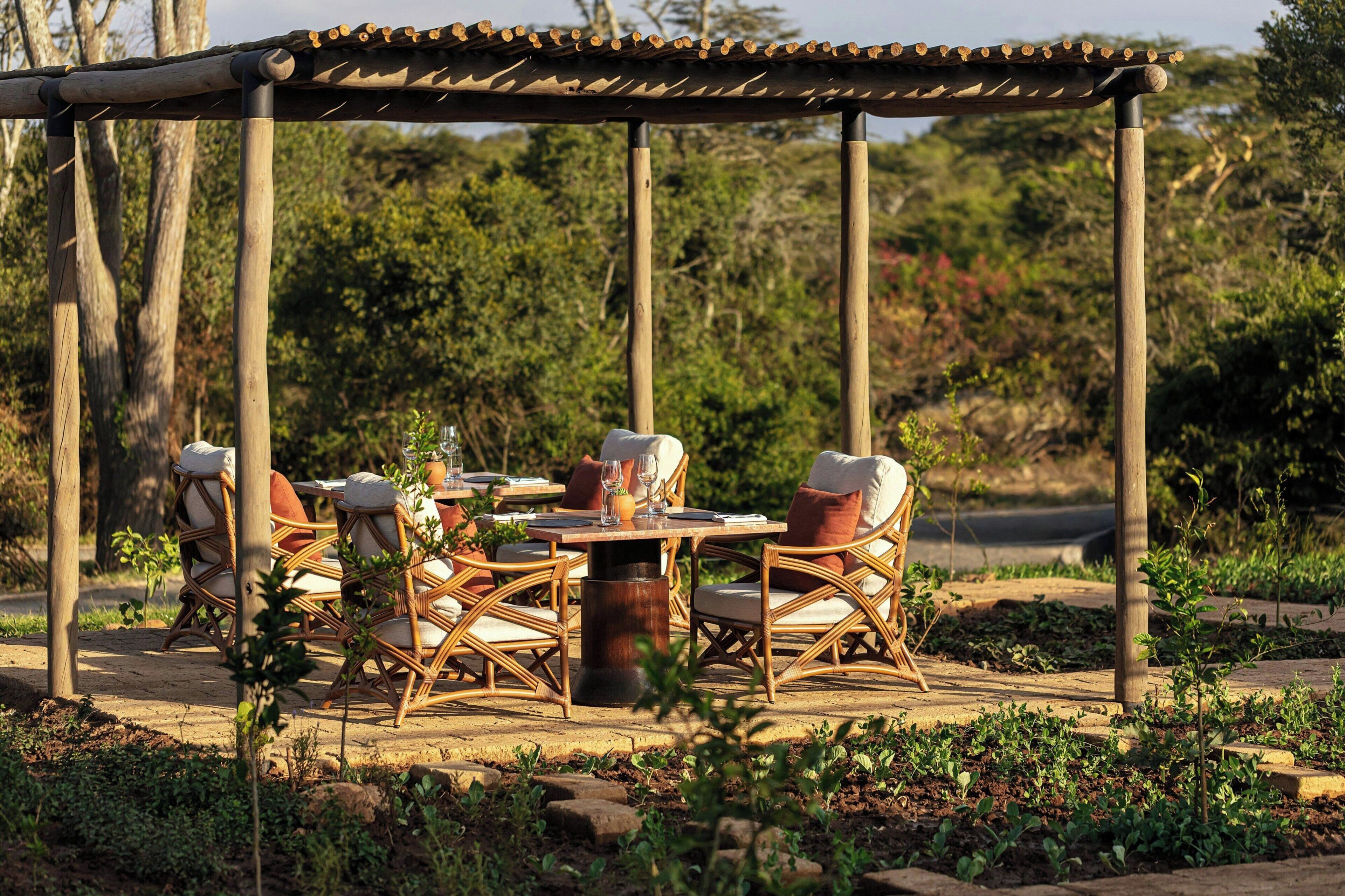 Un área de comedor al aire libre con mobiliario de mimbre y una pérgola.