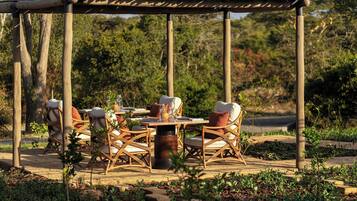 Un área de comedor al aire libre con mobiliario de mimbre y una pérgola.