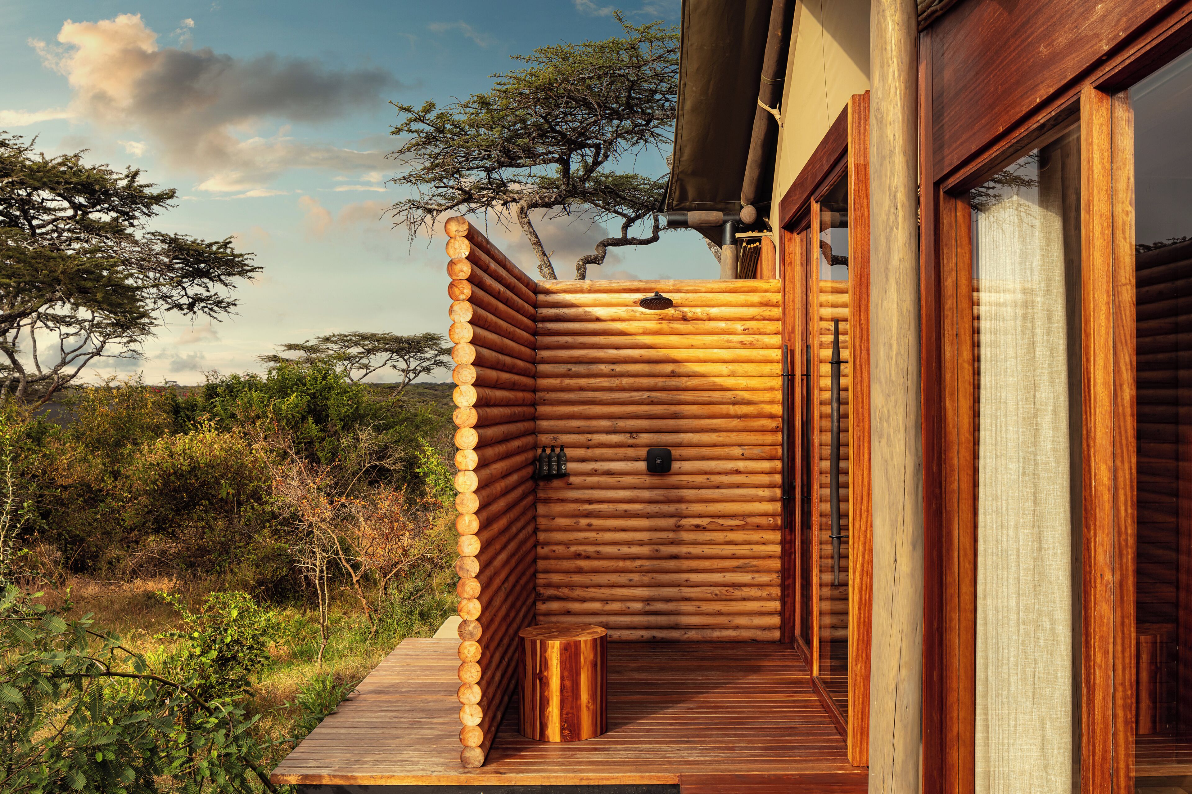 A log cabin with a wooden deck and a small wooden stool.