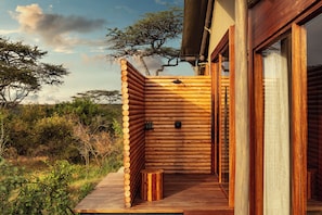 A log cabin with a wooden deck and a small wooden stool. - JW Marriott Mount Kenya Rhino Reserve Safari Camp (Laikipia County)