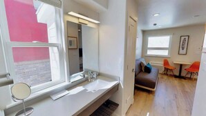 Une salle de bain moderne avec un grand miroir, un lavabo blanc et une fenêtre.