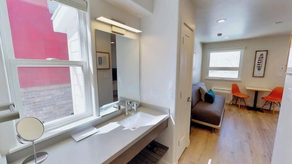 A modern bathroom with a large mirror, a white sink, and a window. - Slot Canyon Unit C, Luxury Condo In Downtown Moab (Moab)