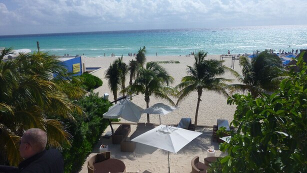 Strandblick mit Palmen, Liegestühlen und Sonnenschirmen.