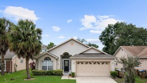 A single-story house with a garage, a front door, and a small front yard with a palm tree. - Indian Ridge - Pool Home Spa, Newly Renovated (Kissimmee)