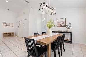 A dining area with a wooden table, black chairs, a white vase with flowers, and a painting on the wall. - Indian Ridge - Pool Home Spa, Newly Renovated (Kissimmee)