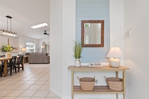 Un intérieur moderne comprenant un coin repas, une console agrémentée de paniers, un miroir et un ventilateur de plafond.