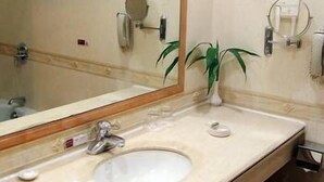 Un baño con un espejo grande, un lavabo, una toalla y una planta en maceta.