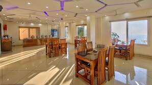 Uma ampla sala de jantar com mobiliário de madeira, um balcão de bar e grandes janelas com vista.