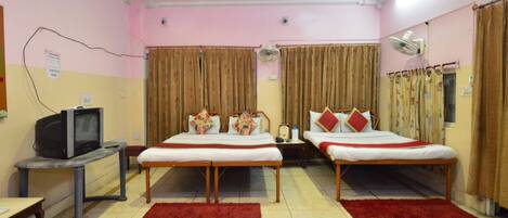 A hotel room with two beds, a TV, a desk, and a red rug.