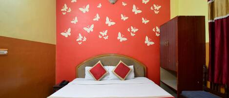 A hotel room with a bed, a wardrobe, and a red wall with butterfly decals.