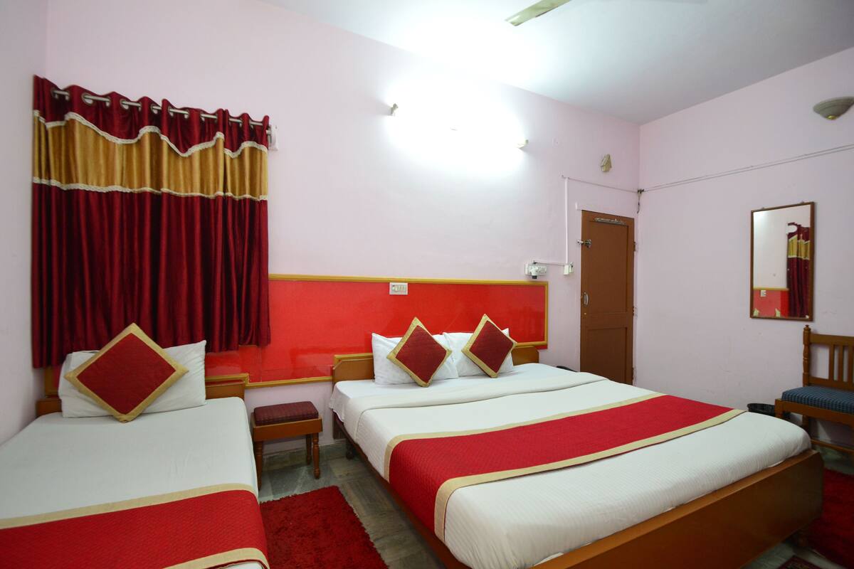 Habitación de hotel con dos camas, una decoración en rojo y blanco y un cabecero de madera.