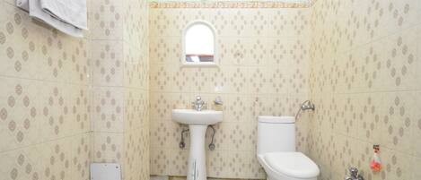 Un baño con baldosas estampadas, un lavamanos pedestal, un inodoro y una ventana.