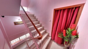 Un escalier rose avec une rampe en bois menant à un palier.