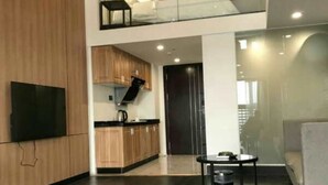 A modern interior with a wooden floor, a kitchen area with wooden cabinets, a dining table, and a flat-screen TV mounted on the wall. - Xitishu Hotel Apartment (Guangzhou)