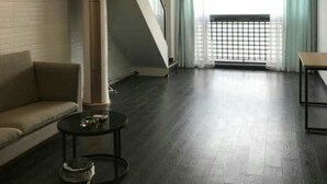 A spacious living area with a high ceiling, a sofa, a coffee table, and a staircase leading to an upper level. - Xitishu Hotel Apartment (Guangzhou)