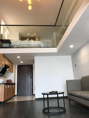 A modern interior with a glass ceiling, a dining area with a round table, a sofa, and a kitchen with wooden cabinets.