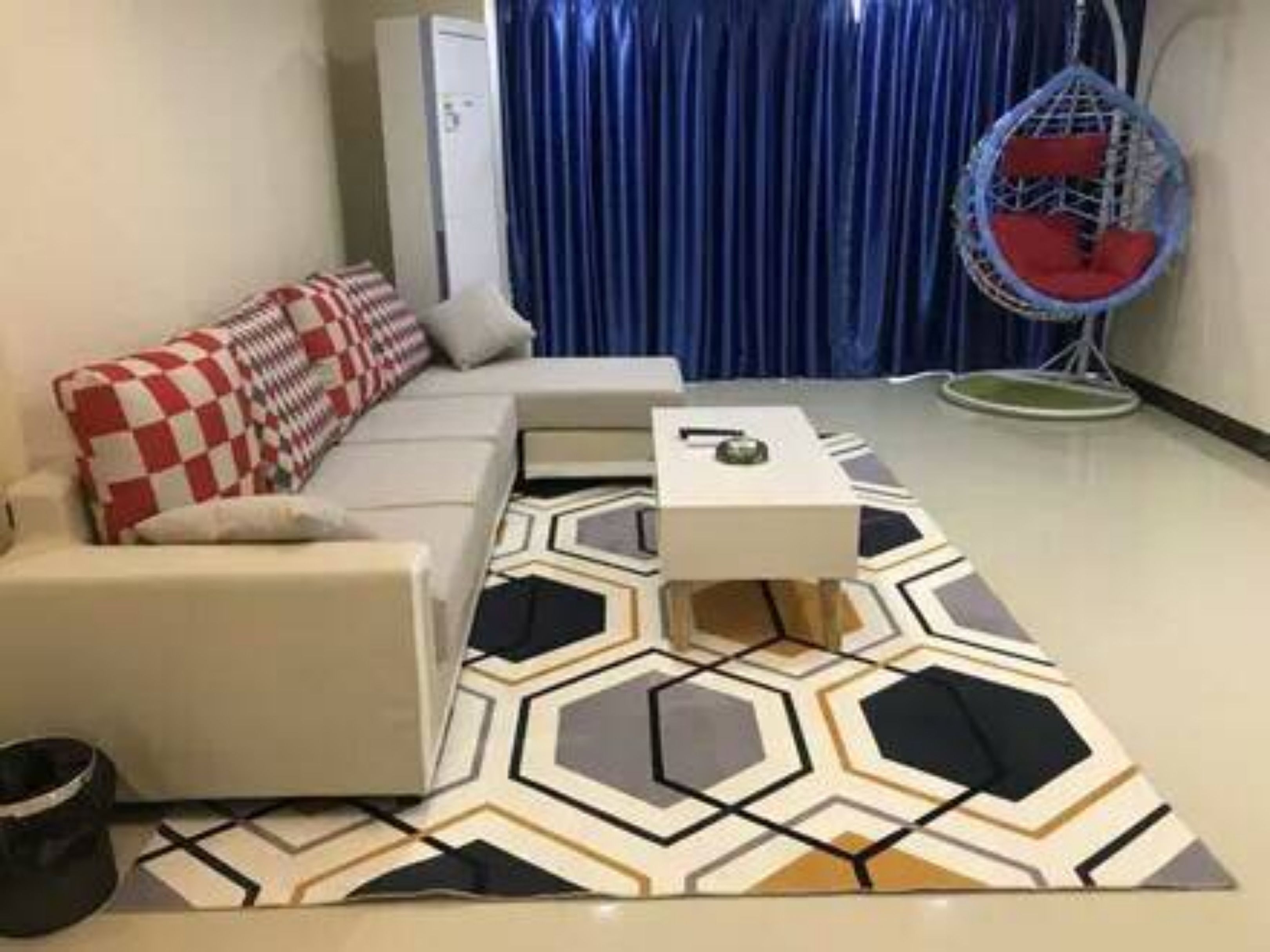 A modern living room with a sofa, a coffee table, and a hanging chair.