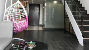 A modern interior with a staircase, a hanging chair, and a bed in the upper room. - Xitishu Hotel Apartment (Guangzhou)