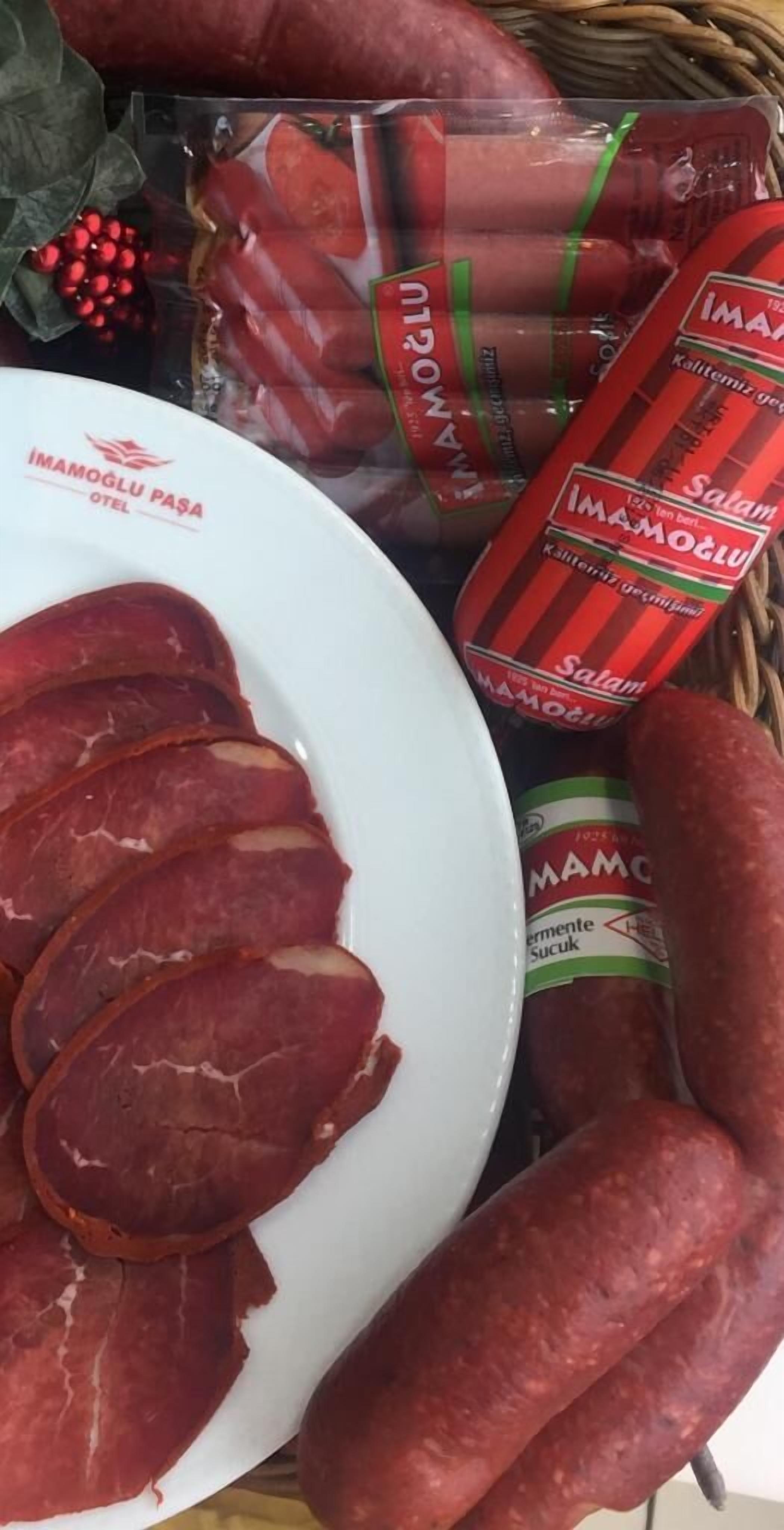A plate with sliced salami, a basket with whole salami, and a package of salami.
