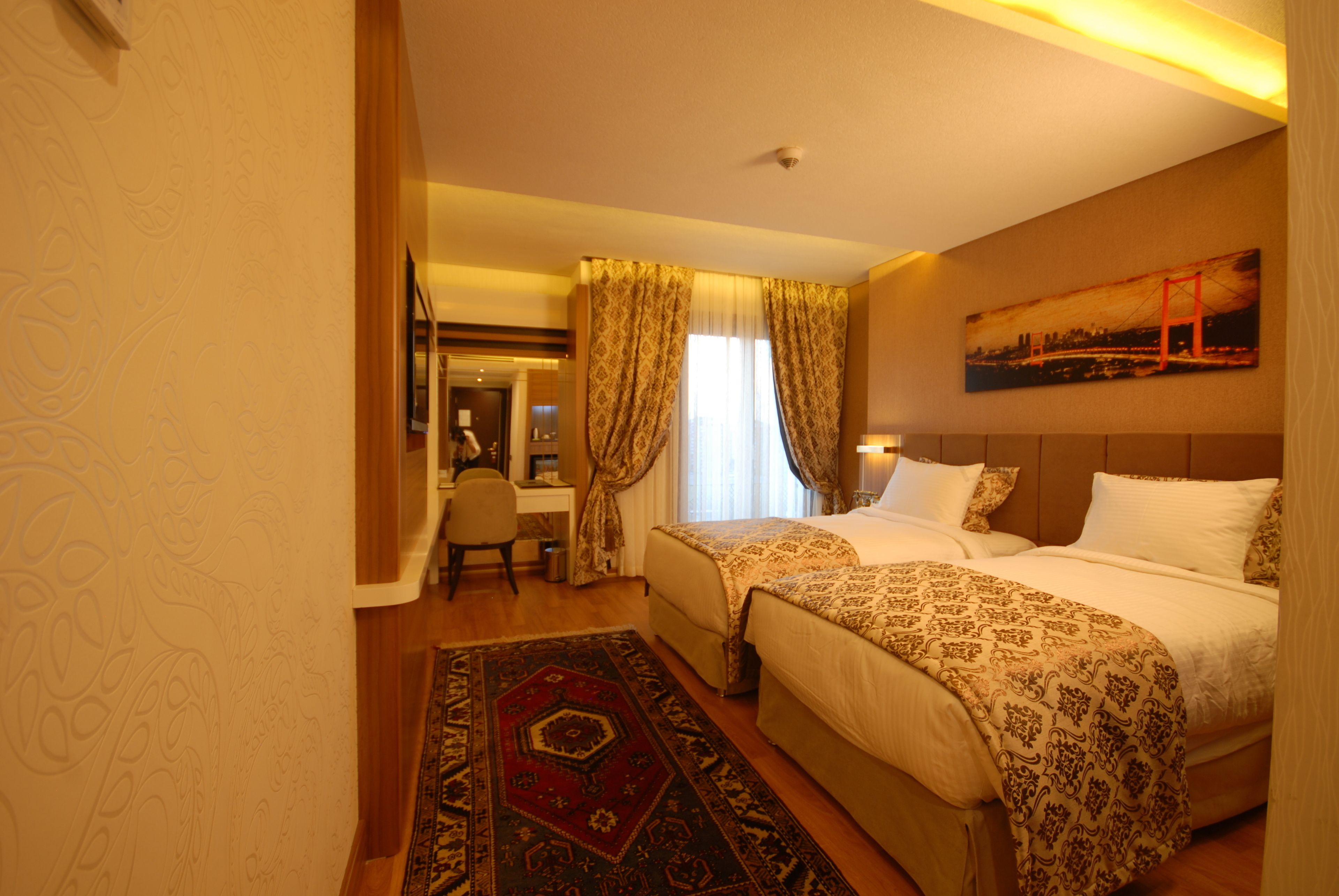 A hotel room with two beds, a desk, and a chair.